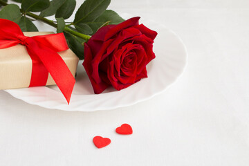 Closeup on festive table setting with red rose and gift