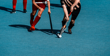 Two field hockey player, fighting for the ball on the midfield during an intense match on artificial grass