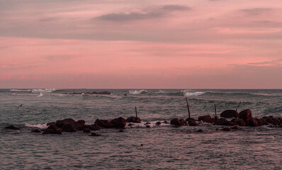 Krajobraz fal na oceanie podczas zachodu słońca przy skalistym wybrzeżu.