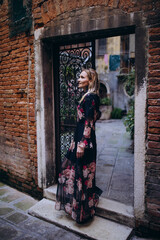 Fototapeta na wymiar The girl walks through the narrow streets. A tourist travels around Venice. Metal fence.