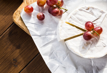 Camembert cheese with red grapes, top view with copy space