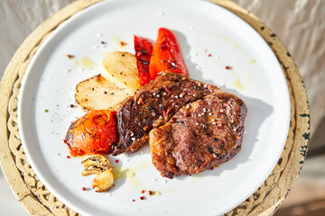 Hot Rib eye steak on white plate. Garnish grilled vegetables. Barbecue restaurant menu.