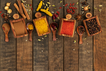 Various spices cinnamon, turmeric, pepper and anise, onions, coriander in wooden boxes on a wooden table