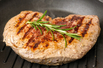 Fried beef steak in the grill pan with rosemary. Healthy dinner concept. 