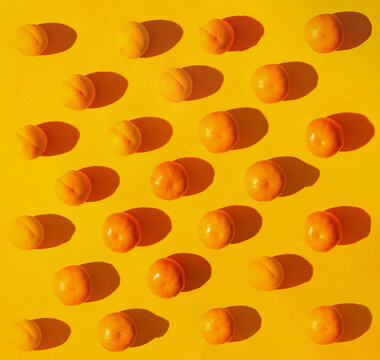 Flat lay pattern of fresh organic natural tangerines and apricots. Bright yellow background.