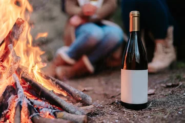 Foto auf Alu-Dibond BClose-up bottle of wine with copy space with fire and people in background. © Pintau Studio