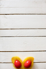 Two red  Easter eggs as bunny ears on a white wooden background. Creative concept.