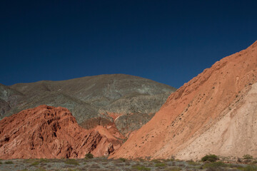 Desert arid landscape. View of the orange rocky formations and mountains under a deep blue sky. 