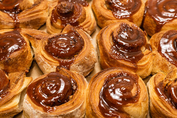 Homemade cinnamon buns with spices and caramel on parchment paper.