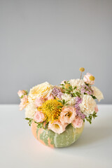 Flowers arrangement in pumpkin on the white table. Fresh cut flowers for decoration home. European...