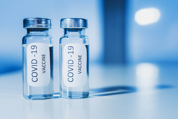 Vaccine against coronavirus COVID-19 in an ampoule on a blue background close-up.