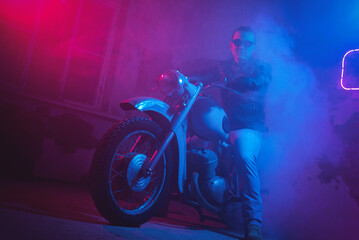 Plakat Motor biker in the neon lights in the old garage.