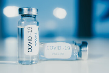Vaccine against coronavirus COVID-19 in an ampoule on a blue background close-up.
