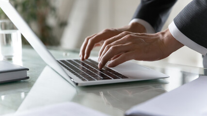 Close up businessman using laptop in office, typing on keyboard, employee accountant writing email...