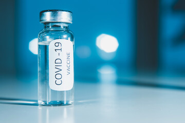 Vaccination against coronavirus COVID - 19. Vial on a blue background close-up. Concept.