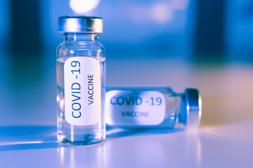 Vaccination against coronavirus COVID - 19. Vial on a blue background close-up. Concept.