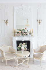 luxurious light interior in the Baroque style. A spacious room with a road chic beautiful furniture, a fireplace and flowers. plant stucco on the walls and light wood parquet
