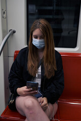 A beautiful white Latina woman using the city subway while writing a text message on her phone