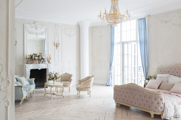 luxurious light interior in the Baroque style. A spacious room with a road chic beautiful furniture, a fireplace and flowers. plant stucco on the walls and light wood parquet