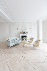 luxurious light interior in the Baroque style. A spacious room with a road chic beautiful furniture, a fireplace and flowers. plant stucco on the walls and light wood parquet