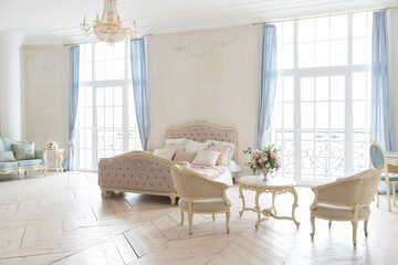 luxurious light interior in the Baroque style. A spacious room with a road chic beautiful furniture, a fireplace and flowers. plant stucco on the walls and light wood parquet