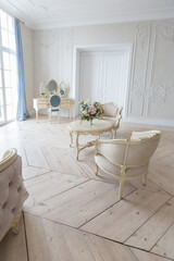 luxurious light interior in the Baroque style. A spacious room with a road chic beautiful furniture, a fireplace and flowers. plant stucco on the walls and light wood parquet