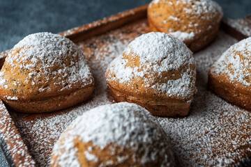 Homemade cakes, muffins with powdered sugar, on a wooden board, on a blue background