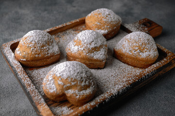 Homemade cakes, muffins with powdered sugar, on a wooden board, on a gray background