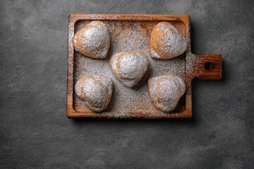 Homemade cakes, muffins with powdered sugar, on a wooden board, on a gray background