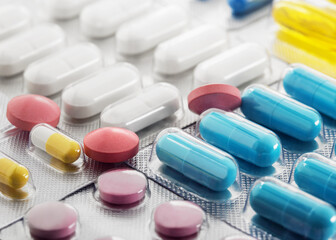 A bunch of medical pills in yellow and other colors. Tablets in plastic packaging.