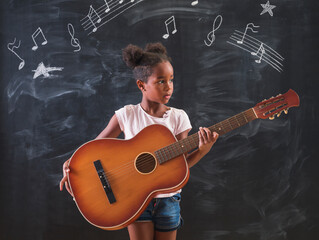 Mixed race schoolgirl playing the guitar while in music school