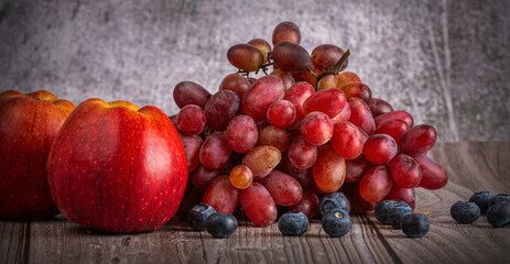 red apples and grapes on dark wood background