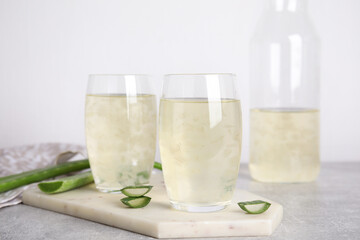 Fresh aloe drink in glasses on light grey table