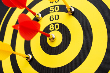 Closeup of a dartboard with yellow and red magnetic darts. Dart in bulls eye of dartboard concept for hitting target dart success concept