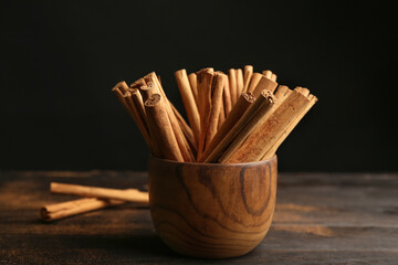 Aromatic cinnamon sticks on wooden table against black background