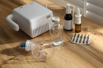 Fototapeta na wymiar Modern nebulizer with face mask and medications on wooden table indoors. Inhalation equipment