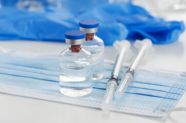 Vaccine and Healthcare Medical concept. Vaccines, medical gloves, surgical mask and syringes on white background for prevention, immunization and treatment from corona virus infection.  flat lay