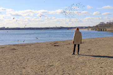 Woman bundled up and walking on a beach in winter