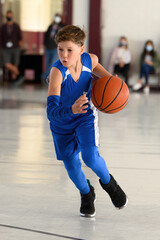 Young athletic boy playing in a game of basketball