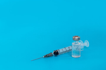 Medicine infectious concept. Vaccine and syringe injection on blue background. Its uses for prevention, immunization, and treatment.