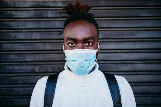 Young man with protective face mask against corrugated wall