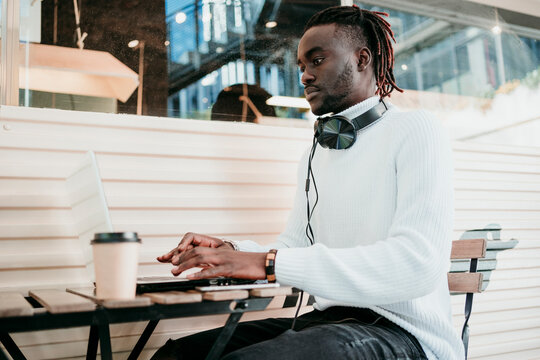 Creative businessman with disposable coffee cup working on laptop in cafe