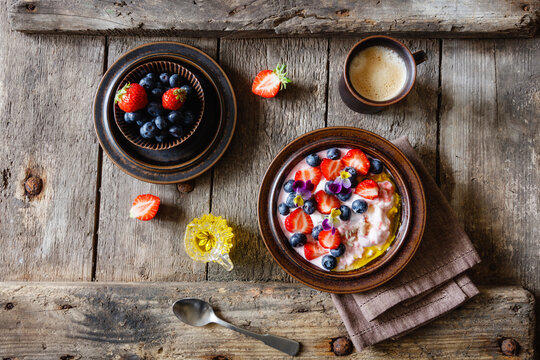 Cup of coffee and plate of quark with strawberries, blueberries and edible flowers