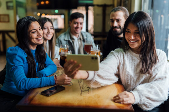 Smiling friends taking selfie on smart phone in bar