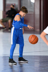 Young athletic boy playing in a game of basketball