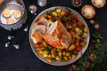 Roasted turkey breast with potatoes, carrots, turnip and brussel sprouts. Christmas dinner table with decorations. View from above
