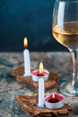 Glass of white wine and candles on marble table