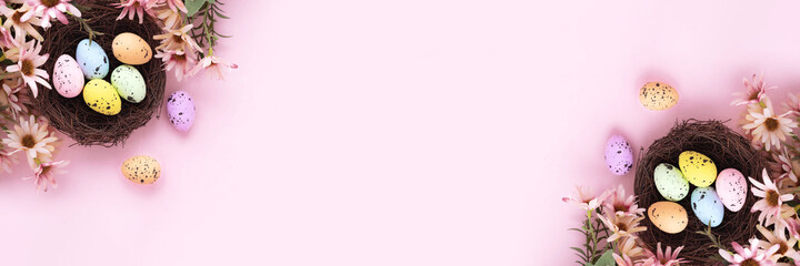 Obraz premium Colorful easter eggs in nest and flowers on pink background with copy space. Flat lay. Banner.