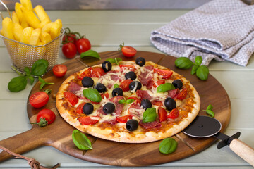Delicious pizza served on wooden pizza board, french fries