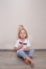 little girl B is sitting on the floor of the room against the wall.